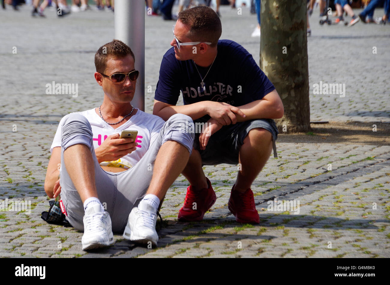 Due uomini seduti sulla strada e in attesa per il Düsseldorf gay parade - Christopher Street Day - per iniziare Foto Stock