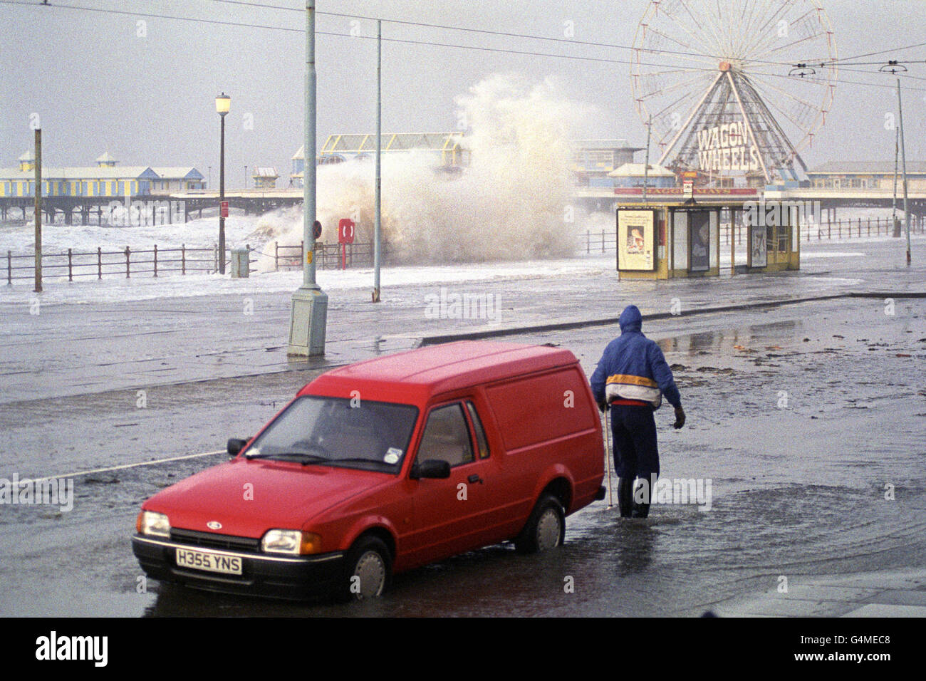 Un residente di Blackpool guarda un'enorme onda palude la passeggiata come vento di forza di Gale e un'alta marea combinata, causare il caos per coloro che vivono vicino al mare. Foto Stock