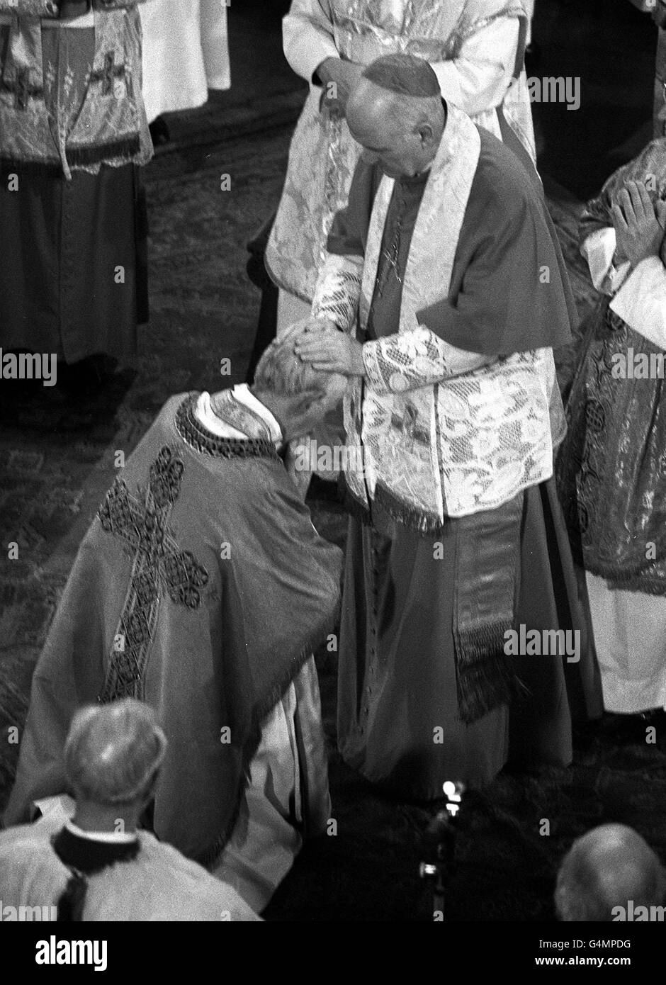 George Basil Hume, 53 anni, ex Abate di Ampleforth, si inginocchia davanti a sua Eminenza il Cardinale William Conway, Primate di tutta l'Irlanda, durante la cerimonia a Westminister Catherdral, dove il monaco è stato intronizzato come leader di 5 m cattolici in Inghilterra e Galles. Foto Stock