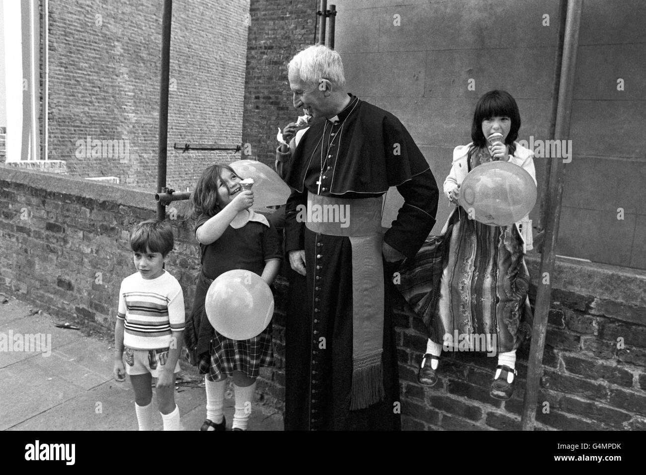 Il Cardinale Hume, Arcivescovo di Westminster, con Simone Parrish (L) di otto anni al Carnevale di Notting Hill. Il cardinale Hume stava assistendo ad un servizio all'aperto in una chiesa nel cuore della zona di carnevale. Foto Stock