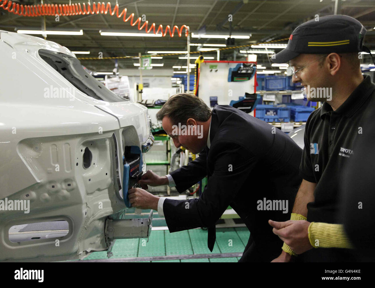 Il primo ministro David Cameron installa un badge su un'auto presso la fabbrica Toyota di Burnaston. Foto Stock