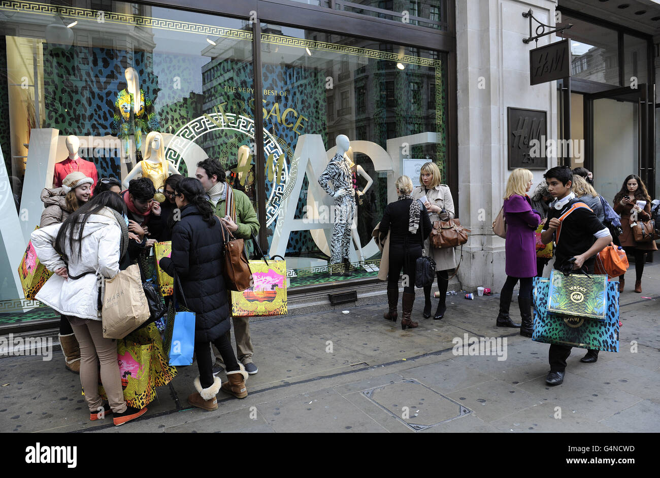 Gli acquirenti lasciano il negozio H&M a Regent Street, Londra, dopo aver acquistato abiti firmati Versace. Foto Stock