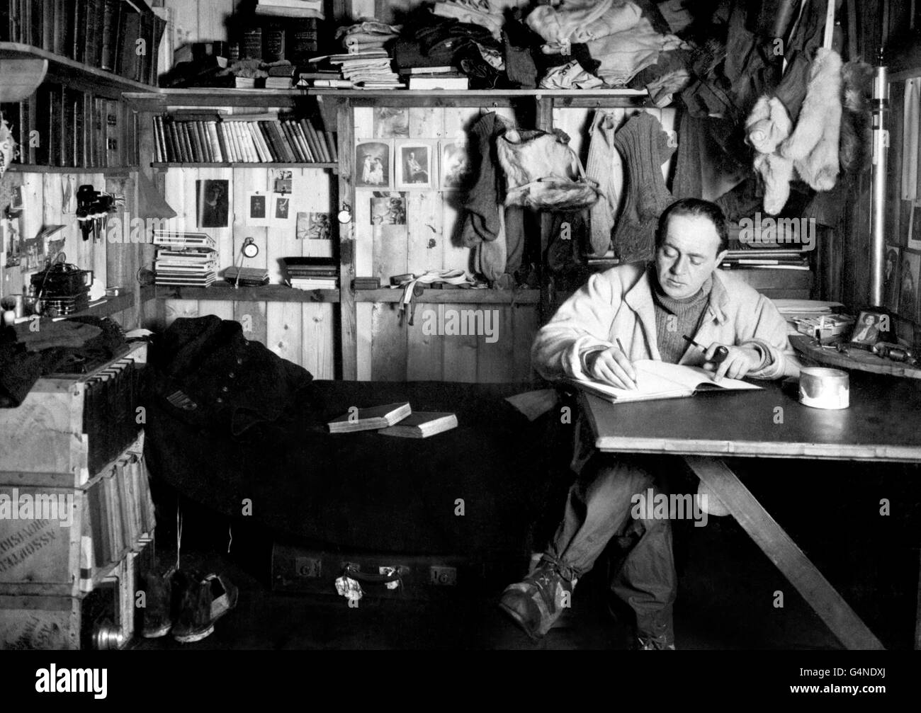 Il capitano Robert Falcon Scott scrive ad un tavolo nei suoi quartieri (conosciuto come il suo 'den') al campo base britannico in Antartide. Scott e il suo partito sono morti nel viaggio di ritorno dopo il loro fallito tentativo di essere il primo a raggiungere il Polo Sud. Foto Stock
