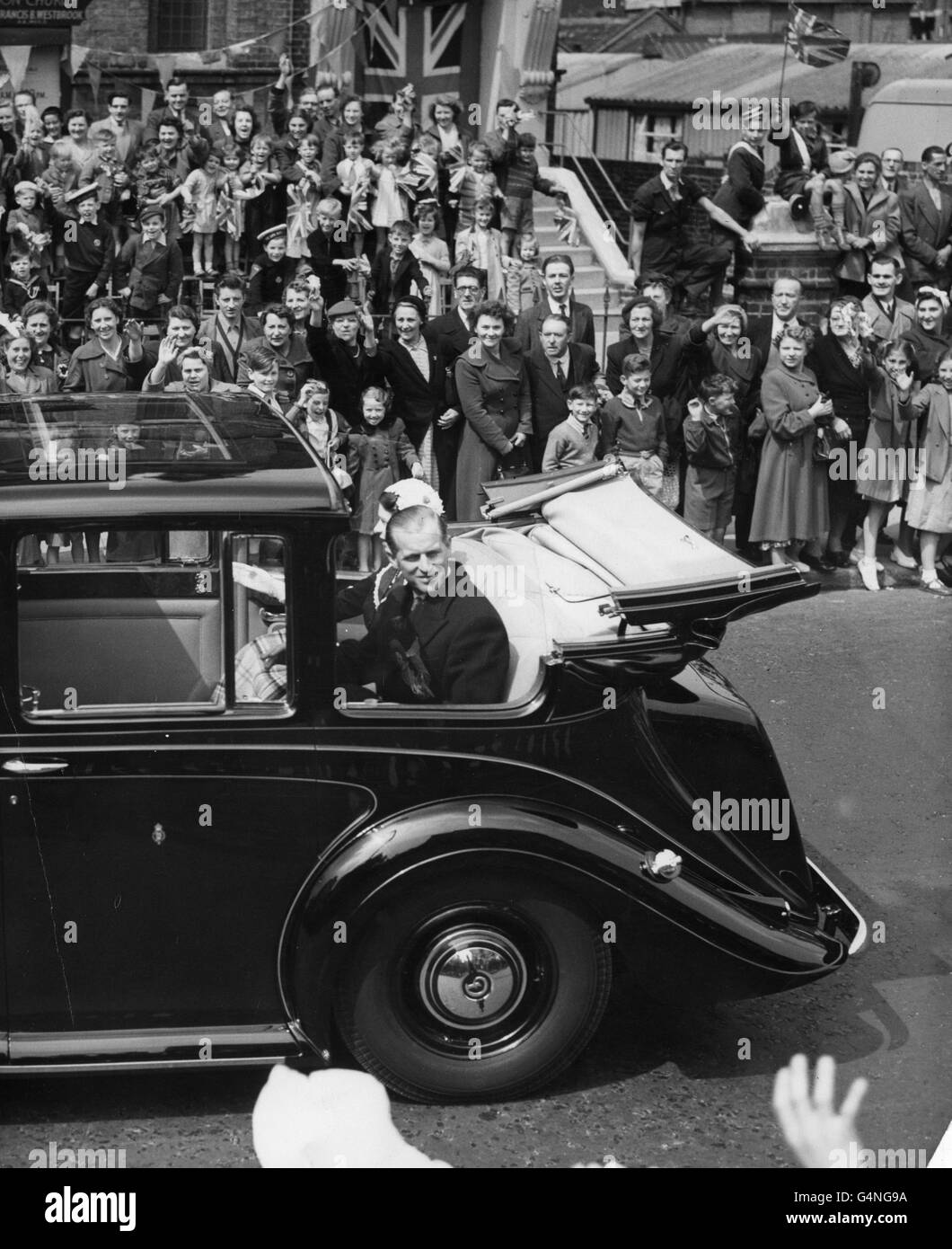 I bambini si uniscono alle grazie, mentre le grandi folle acclamano la Regina e il Duca di Edimburgo mentre guidano attraverso Fulham Palace Road durante il loro tour a nord-ovest di Londra. Foto Stock
