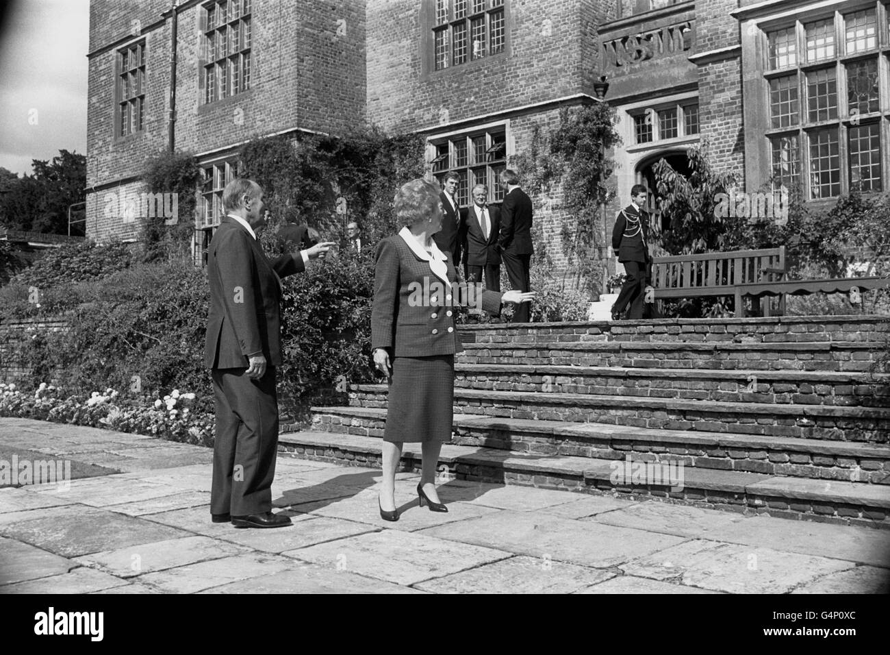 Il primo ministro Margaret Thatcher e il presidente francese Francois Mitterrand indicano i confini dei fiori a Chequers che hanno discusso quando lo ha mostrato intorno ai motivi della sua residenza ufficiale di campagna nel Buckinghamshire. È stato lì per i colloqui bilaterali di routine due volte l'anno ed è stato accompagnato dal suo ministro degli Esteri, Roland Dumas (centro del gruppo di background), che era lì per i colloqui con il segretario agli Esteri John Major (diritto di gruppo). Foto Stock