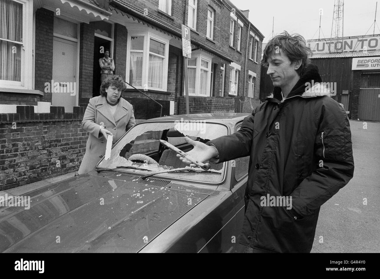 Due residenti di Ivy Road, che conduce da Luton Town's Ground, Dennis Midwinter, 33, e sua moglie Christine mostrano alcuni dei risultati della violenza subita in strada la notte scorsa causata da tifosi che partono dopo la partita della fa Cup contro Millwall. Dennis tiene la cerniera di ferro che lo ha colpito sulla testa come si levano accanto al loro parabrezza auto frantumato. La partita è stata interrotta quando i tifosi si sono rovesciati sul campo. I fan di Millwall avevano invaso il campo mezz'ora prima del calcio d'inizio, tornando alle terrazze dopo un appello personale del manager di Millwall George Graham. Foto Stock