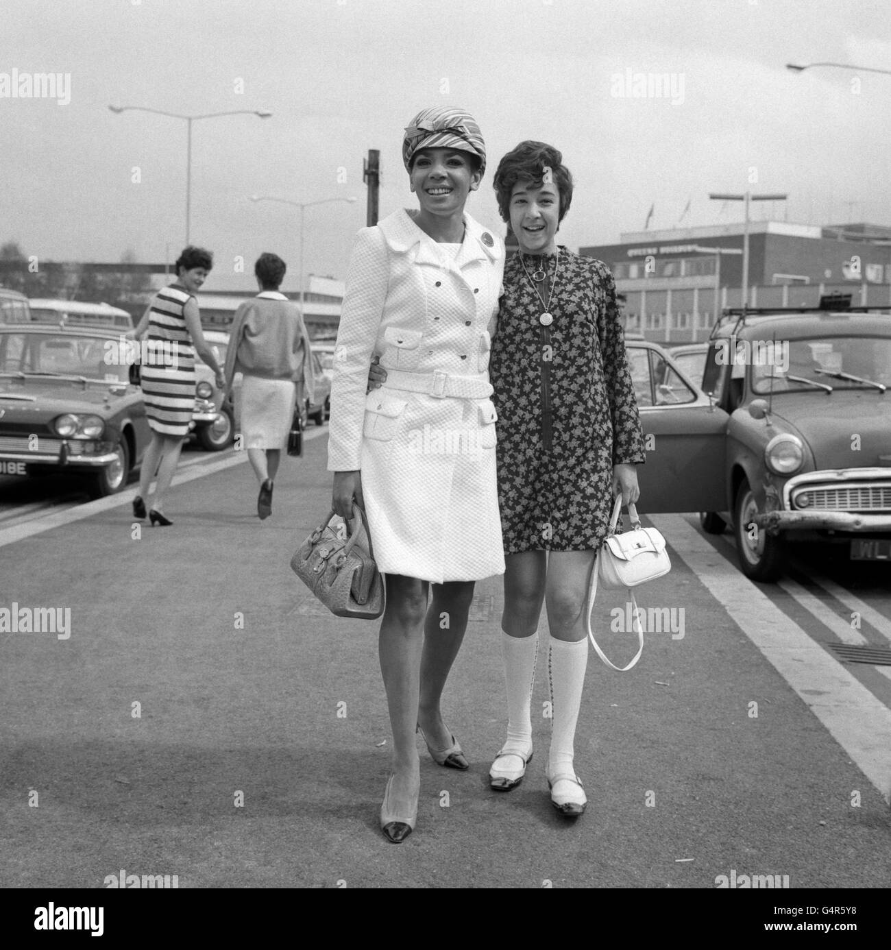 Welsh Singer Shirley Bassey raffigurato con la figlia Sharon (12) all'aeroporto di Heathrow. Dovevano imbarcarsi su un volo per Monte Carlo per assistere ad uno spettacolo di gala, seguito da una vacanza a Monaco. Shirley indossa un cappotto bianco e una berretto gay a strisce di caramelle. Foto Stock