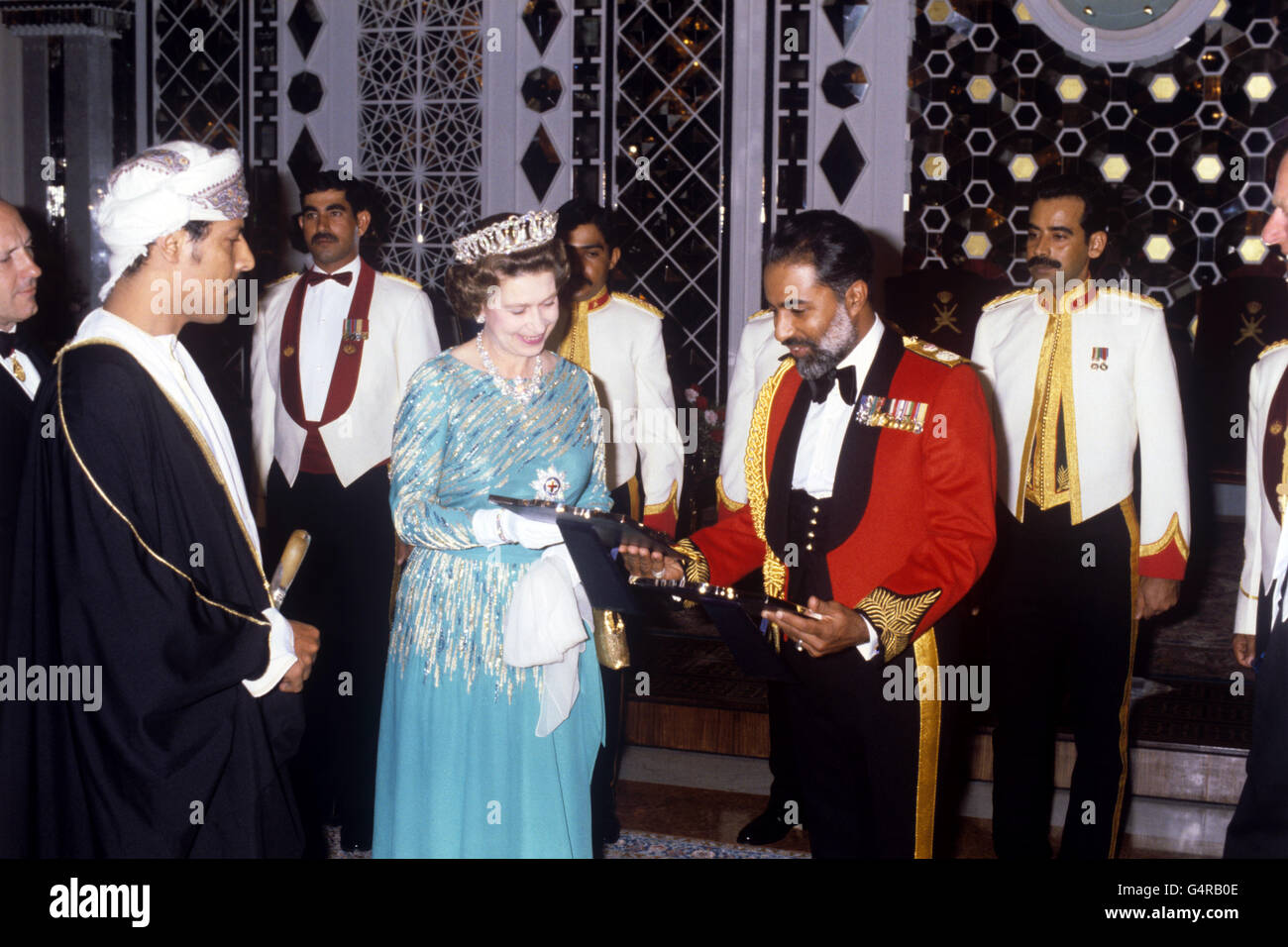 La regina Elisabetta II scambia regali con il sultano di Oman, il sultano Qaboos bin Said, in giacca rossa, durante una cena al Mascate Palace di Oman. Foto Stock
