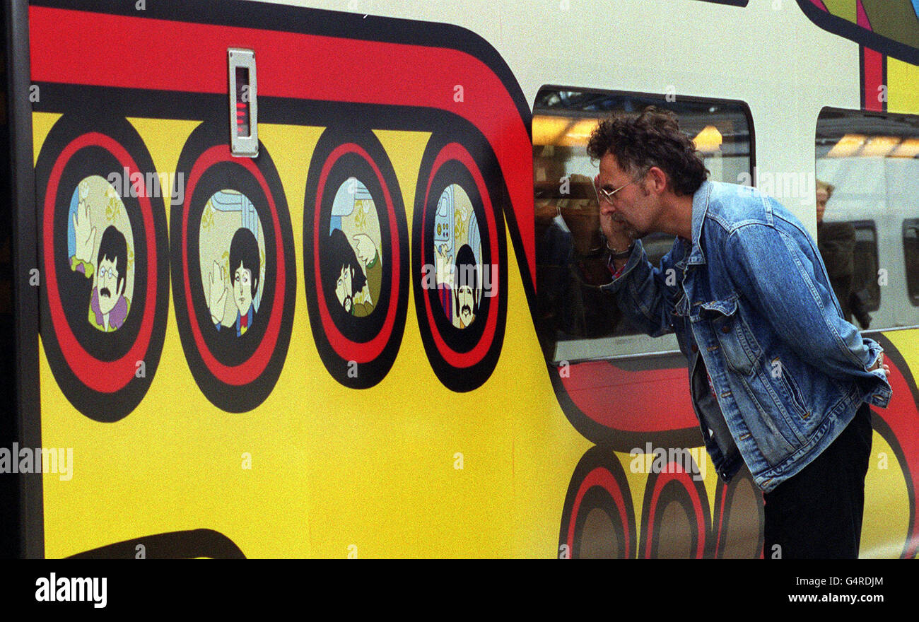 Un passeggero esamina un treno Euro Star recentemente dipinto alla stazione di Waterloo a Londra, decorato con immagini del film dei Beatles Yellow Submarine e rinominato Beatles Express. L-R: John Lennon, Paul McCartney, George Harrison e Ringo Starr. Foto Stock