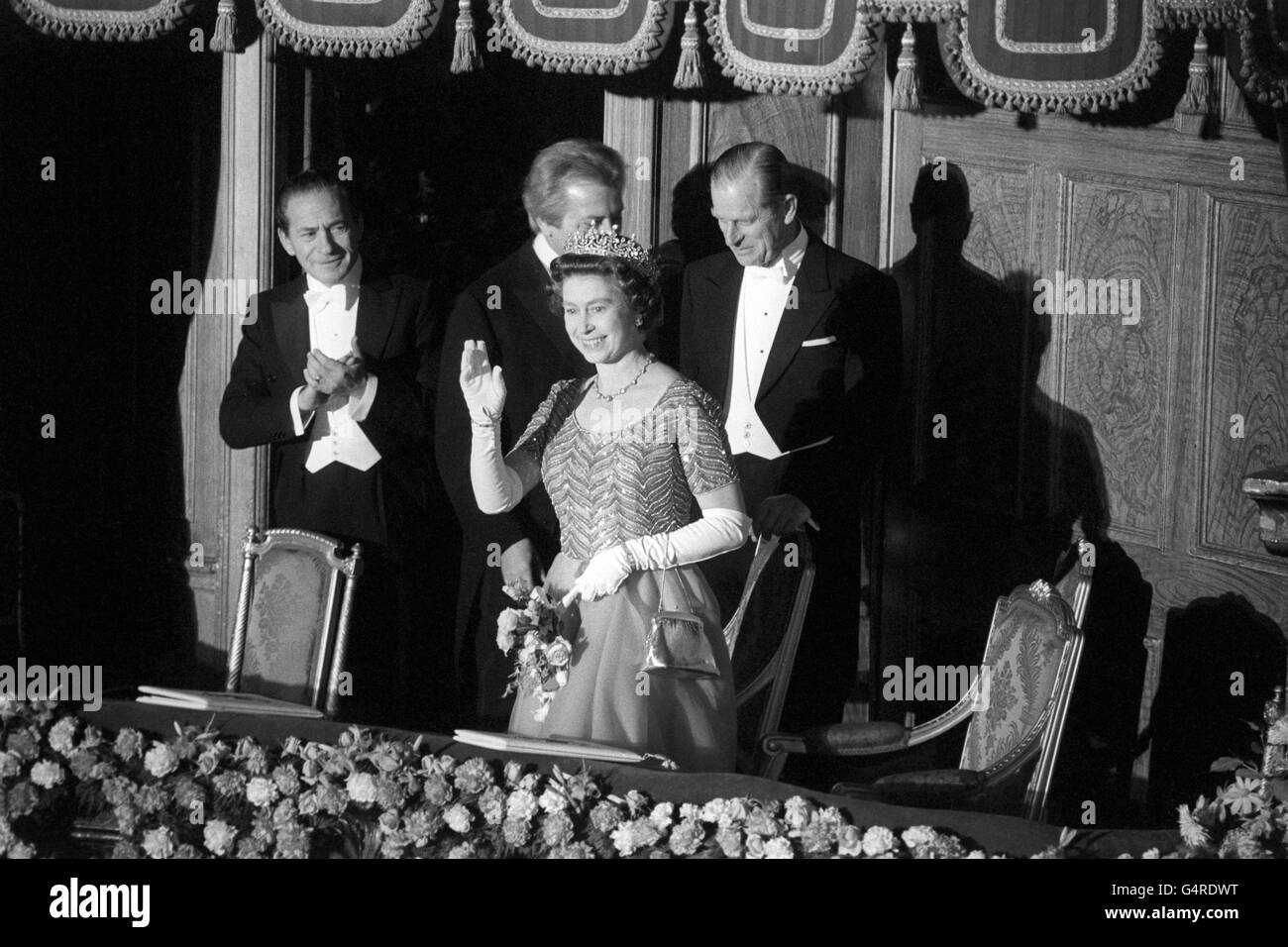 La regina Elisabetta II si rivolge al pubblico dal Royal Box al London Palladium prima dell'inizio della Royal Variety Performance. Fu accompagnata dal Duca di Edimburgo, a destra. Foto Stock
