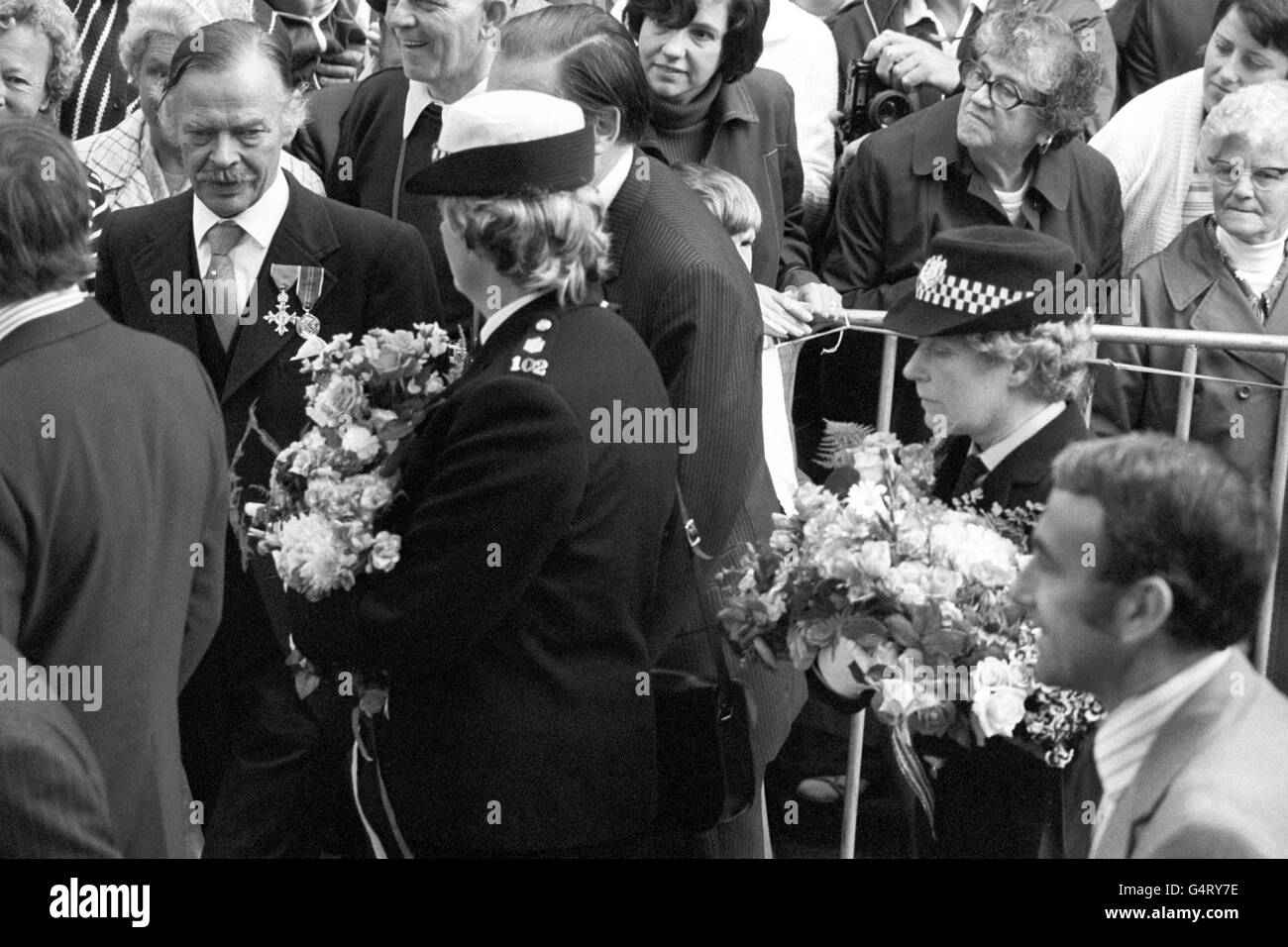 Ufficiali di polizia con armi piene di fiori che erano stati dati alla regina Elisabetta II in una passeggiata nel porto di San Pietro, durante la sua visita all'isola di Guernsey, Isole del canale. Foto Stock