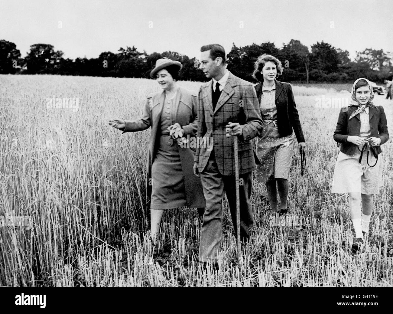 Lontano dalle turbolenze della seconda guerra mondiale, Re Giorgio VI e la Regina Elisabetta camminano in un campo con le loro figlie, la Principessa Elisabetta e la Principessa Margherita (a destra). Foto Stock