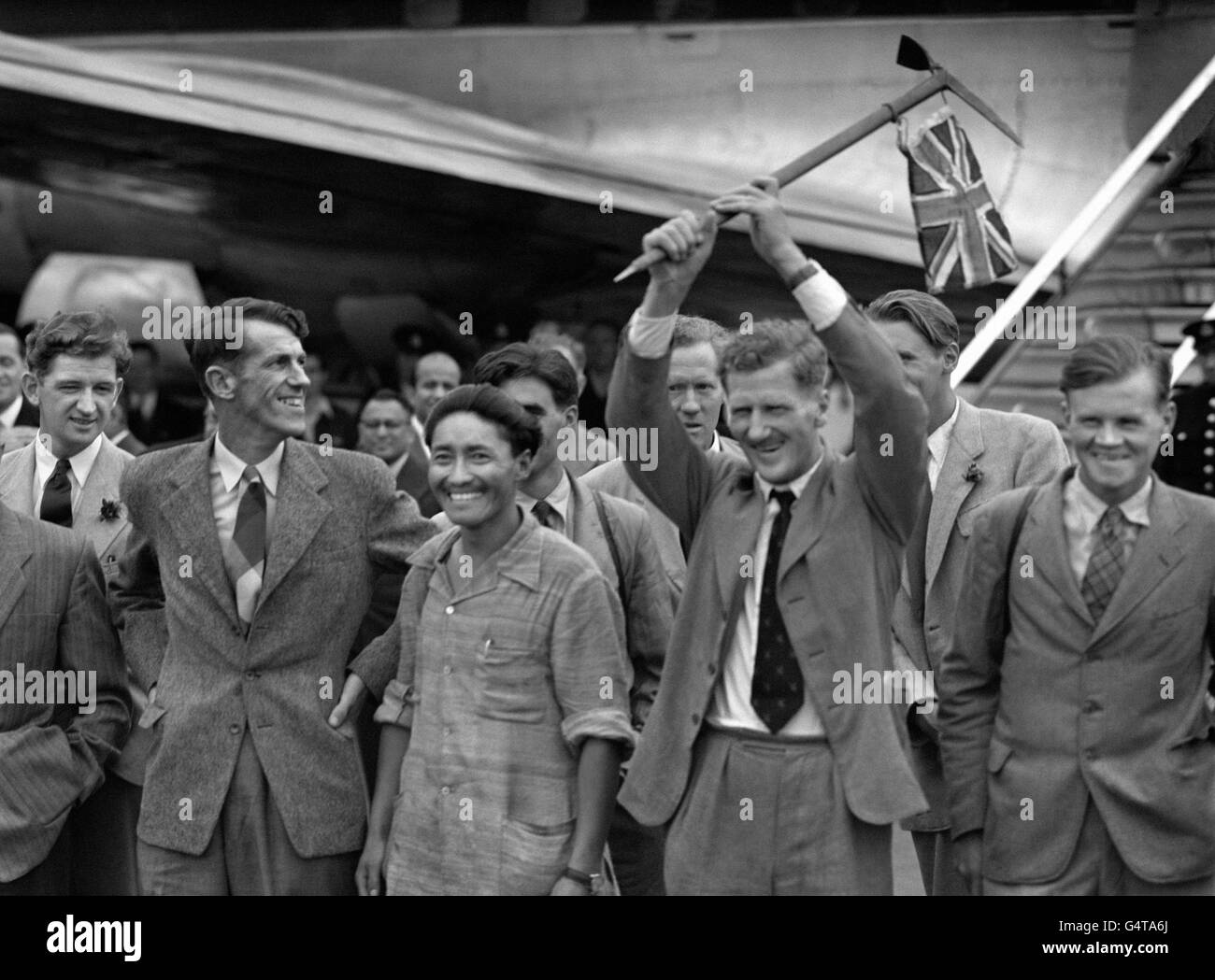 Edmund Hillary della Nuova Zelanda e lo Sherpa Tensing Norgay si sono mossi da un aereo di linea BOAC all'aeroporto di Heathrow a Londra, per ricevere un enorme benvenuto mentre il colonnello John Hunt ondeggia una bandiera dopo la loro salita riuscita della montagna dell'Everest. Foto Stock