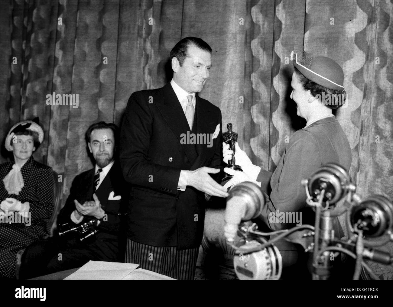 La Sig.ra Lewis Douglas, moglie dell'Ambasciatore degli Stati Uniti che presenta Sir Laurence Olivier con un American Academy Film Awards 'Oscar' per Hamlet all'Odeon Theatre di Londra. Sir Lawrence Oliver ha ricevuto tre premi per gli Oscar Hamlet, Best Film e Best Actor dalla American Academy e il premio Best Film British Academy. Foto Stock