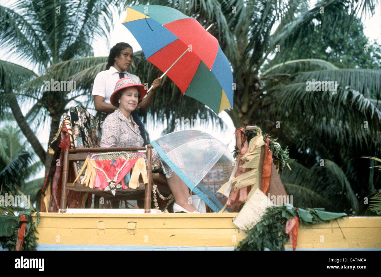 La Regina è portata a spalla in alto in una canoa fino alla riva di Tuvalu alla fine della sua visita alle isole del Mare del Sud. La canoa è stata addlata alla chiatta reale d'attesa con la quale la regina è stata trasferita a HMS Britannia per navigare per Funafuti, un'isola di Corallo del Mare del Sud al largo di Tuvalu. Foto Stock