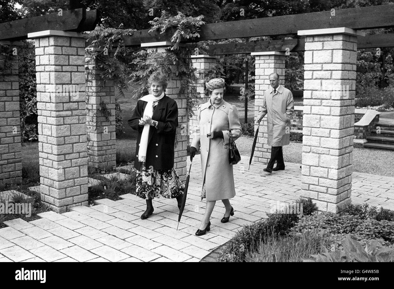 La regina Elisabetta II con l'arcivescovo di Canterbury, la moglie Rosalind Runcie, nei Giardini del Palazzo di Lambeth, seguito dal duca di Edimburgo. La onorevole Runcie aveva raccolto fondi per contribuire alla ricandiera degli antichi giardini. Foto Stock