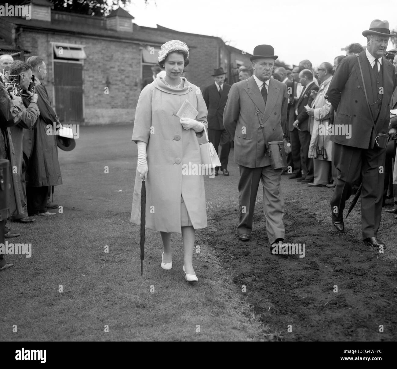 La regina Elisabetta II sulla strada per il paddock alle corse del Sandown Park. Il suo cavallo 'sopra sospetto' stava correndo nelle frappe di Eclipse. Foto Stock
