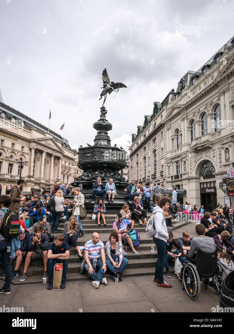Turisti di appoggio sotto la statua di Eros a Piccadilly Circus London REGNO UNITO Foto Stock