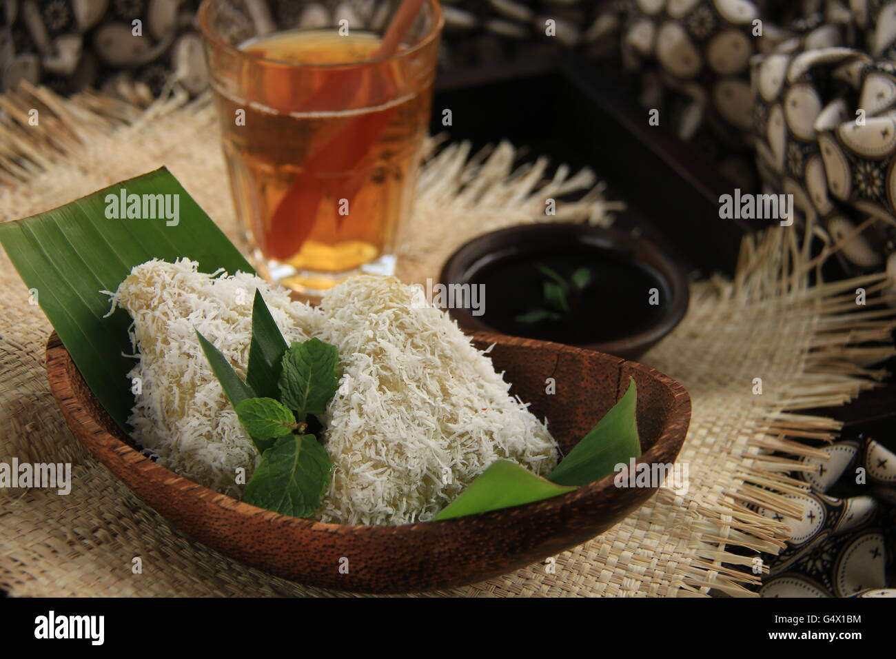 Lupis, tradizionale Giavanese riso glutinoso torta con cocco grattugiato e palm sciroppo di zucchero. Placcata in contemporanea set giavanese. Foto Stock