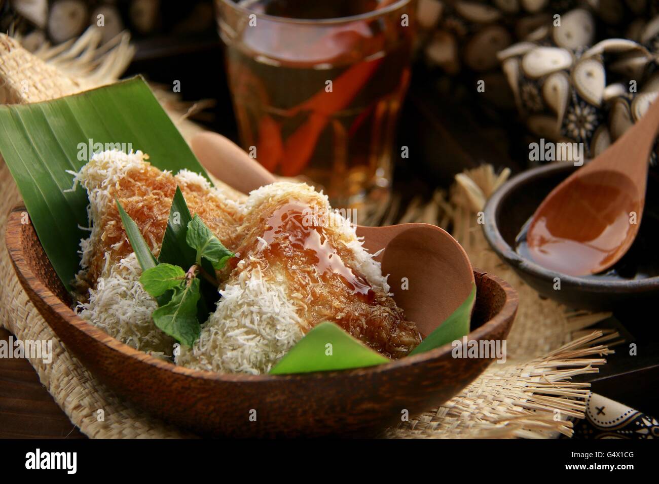Lupis, tradizionale Giavanese riso glutinoso torta con cocco grattugiato e palm sciroppo di zucchero. Placcata in contemporanea set giavanese. Foto Stock