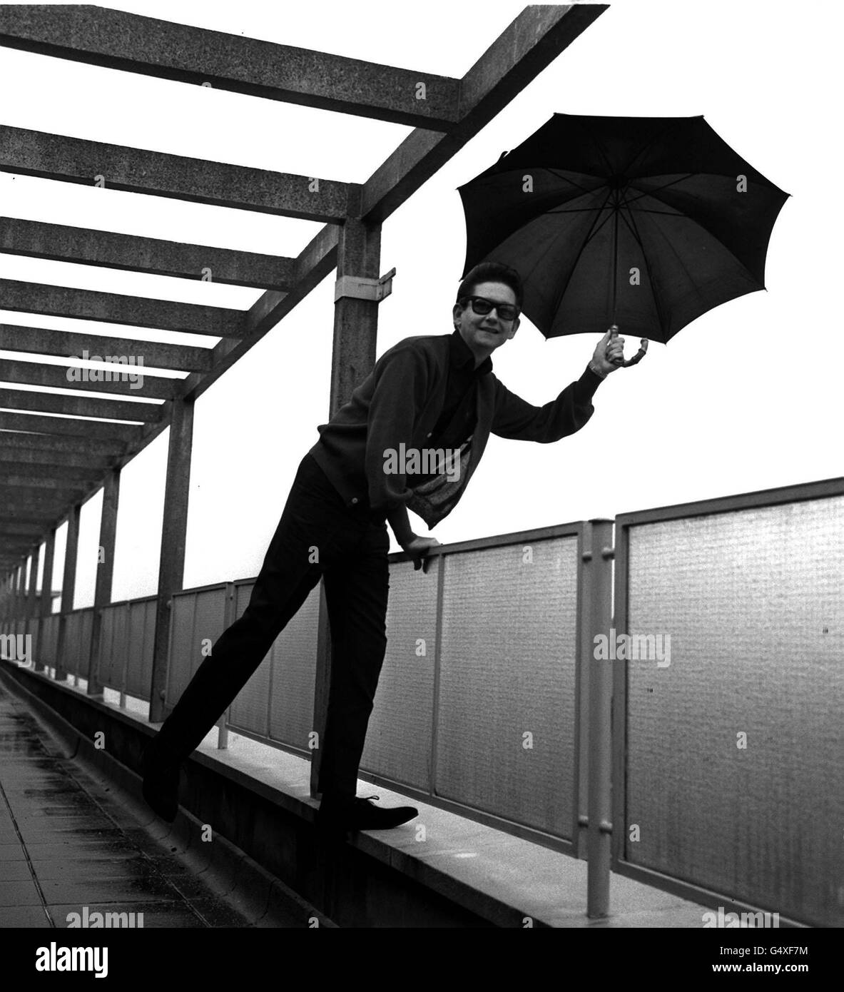 PA NEWS FOTO 14/10/64 AMERICAN POP STAR Roy Orbison i cui "OH! PRETTY WOMAN " è attualmente il vertiginoso aumento nella hit parade di grafici, mette un ombrello fuori sotto la pioggia da ATV House, Londra. Foto Stock