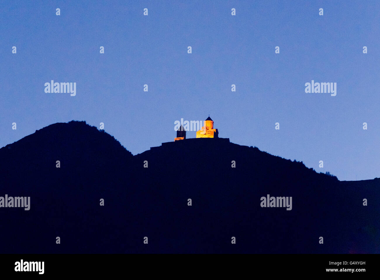 La Georgia, Mtscheta-Mtianeti, Stepanzminda, il monastero Tsminda Sameba illuminata la luce della sera da Gergeti visto Foto Stock