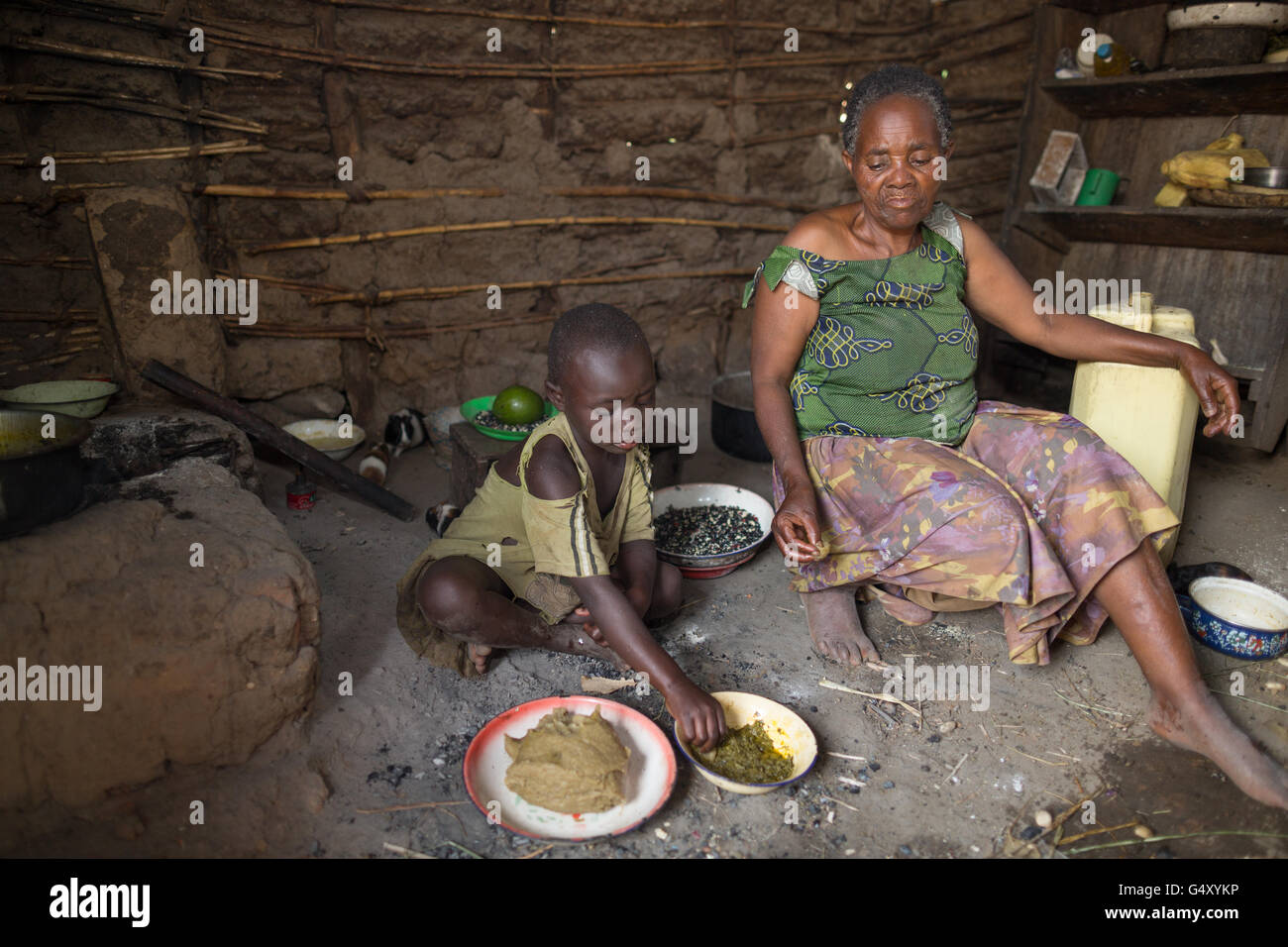 Una madre e un bambino mangiare insieme nella loro cucina in Kasese District, Uganda. Foto Stock