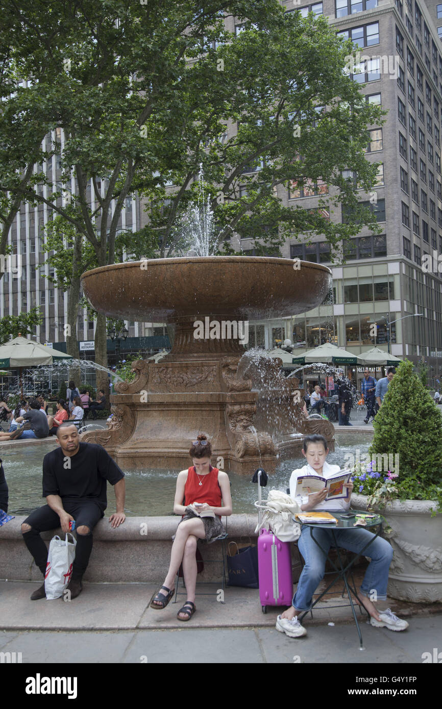 Le persone a rilassarsi in una calda giornata di primavera intorno alla fontana in Bryant Park, Midtown Manhattan. Foto Stock