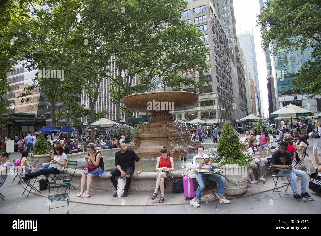 Le persone a rilassarsi in una calda giornata di primavera intorno alla fontana in Bryant Park, Midtown Manhattan. Foto Stock