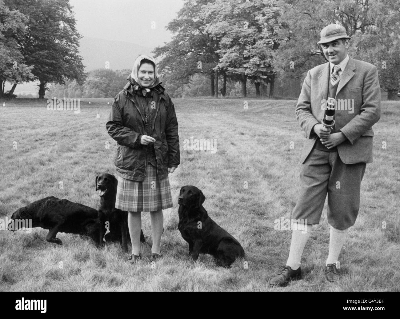 Regina Elisabetta II al Castello Balmoral in Scozia, accompagnata dal suo allenatore di cani e Game Keeper, Bill Meldrum e tre dei suoi cani, Sandringham Sherry (madre di Sandringham Sydney) Sandringham Dipper e il favorito reale Lugwardine Jade, che appartiene al padre di MR Meldrum. Foto Stock