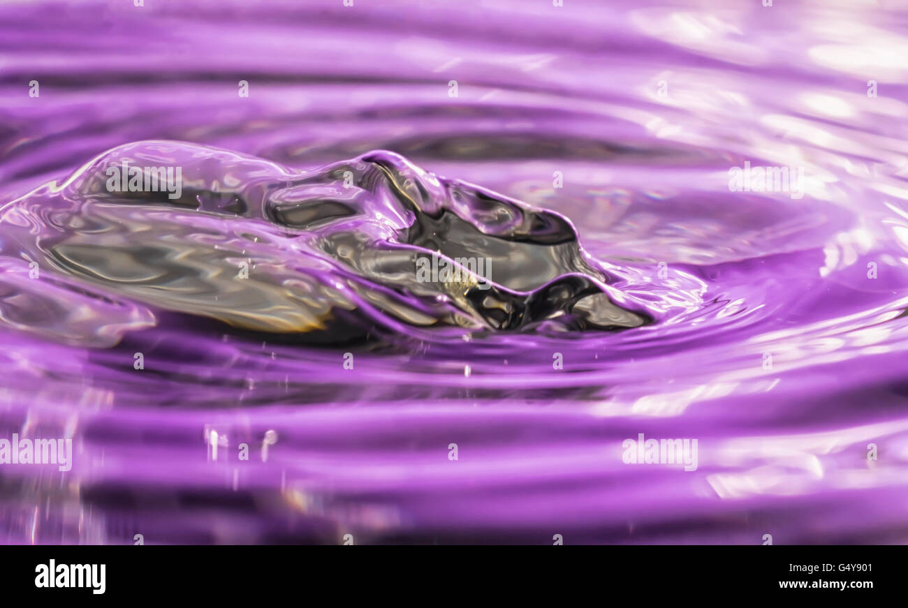 Abstract look metallico immagine dell'onda creato da una goccia di acqua su acqua con riflessi porpora Foto Stock