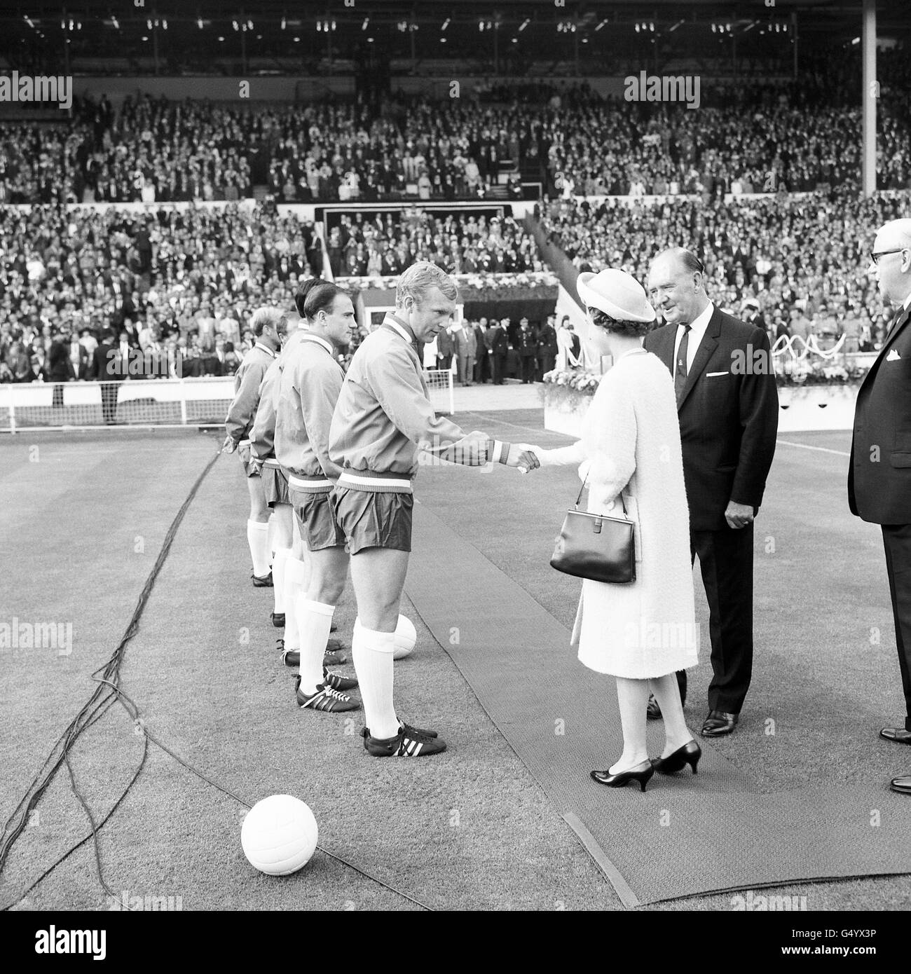 La regina scuotendo le mani con il capitano inglese Bobby Moore quando la squadra inglese e i loro avversari Uruguay sono stati presentati a lei sul campo al Wembley Stadium di Londra dopo aver dichiarato aperta la prima partita della Coppa del mondo del torneo Foto Stock
