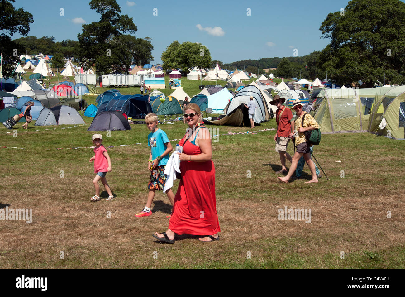 Le famiglie a piedi attraverso il campeggio tende sotto il sole estivo al porto Eliot Festival Cornovaglia Foto Stock