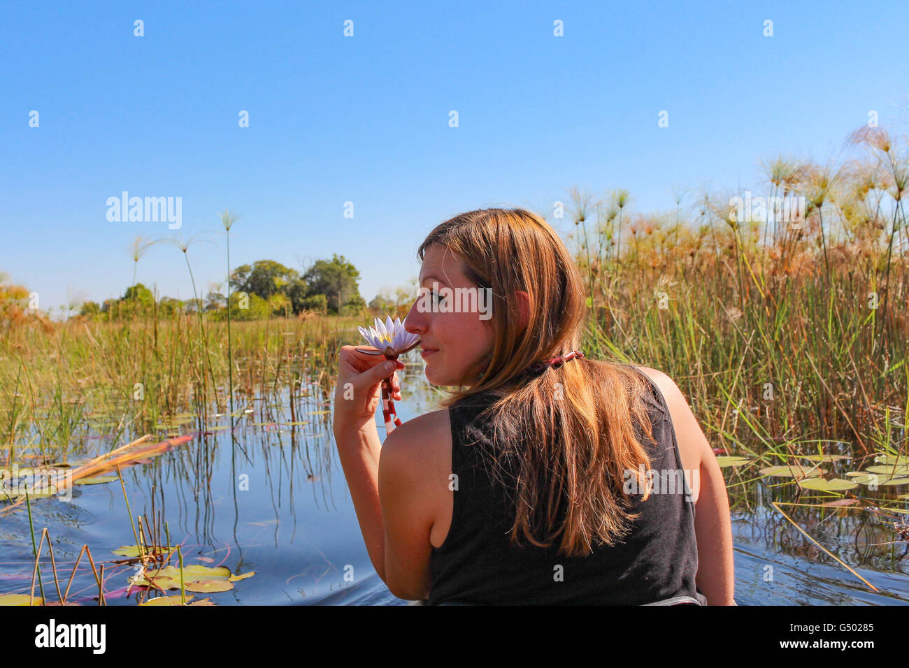 Il Botswana, Okavango Delta, ragazza con mare seros (cyperus papyrus) sul mokoro ride Foto Stock