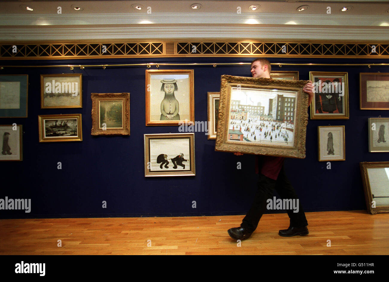 Un portatore di Christie prepara la mostra di venti opere di Laurence Stephen (LS) Lowry presso la casa d'aste nel centro di Londra. I dipinti e il disegno di Lowry, dalla collezione del suo buon amico Monty Bloom, saranno messi in vendita nel giugno 2000. Foto Stock