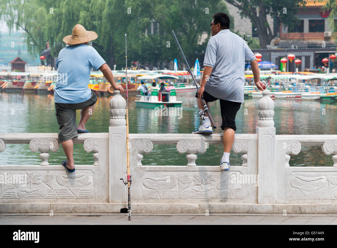 Cina, Pechino, Due pescatori al Waterfront al Lago Qianhai, scena (pedale barca e pescatori) al Lago Qianhai Foto Stock