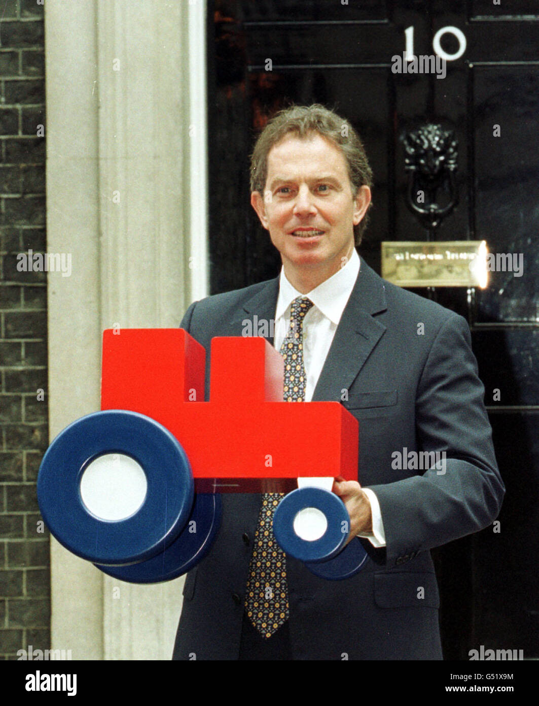 Il primo ministro Tony Blair detiene un trattore modello da rappresentanti dell'industria alimentare, fuori dal 10 Downing Street, Londra. Il trattore, simile al logo British Farm Standard, apparirà sul cibo per indicare che è stato prodotto secondo gli standard specificati. Foto Stock