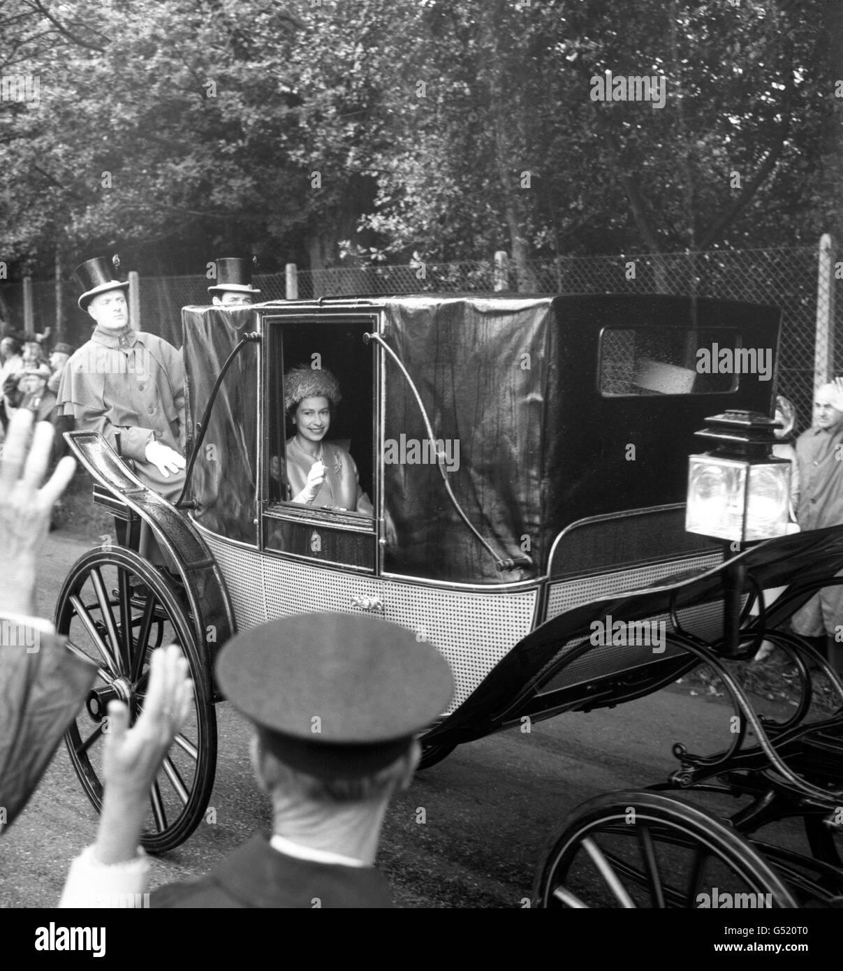 La regina Elisabetta II sorride attraverso la finestra di una carrozza chiusa quando è arrivata sotto la pioggia per il secondo giorno della riunione di Royal Ascot. Foto Stock