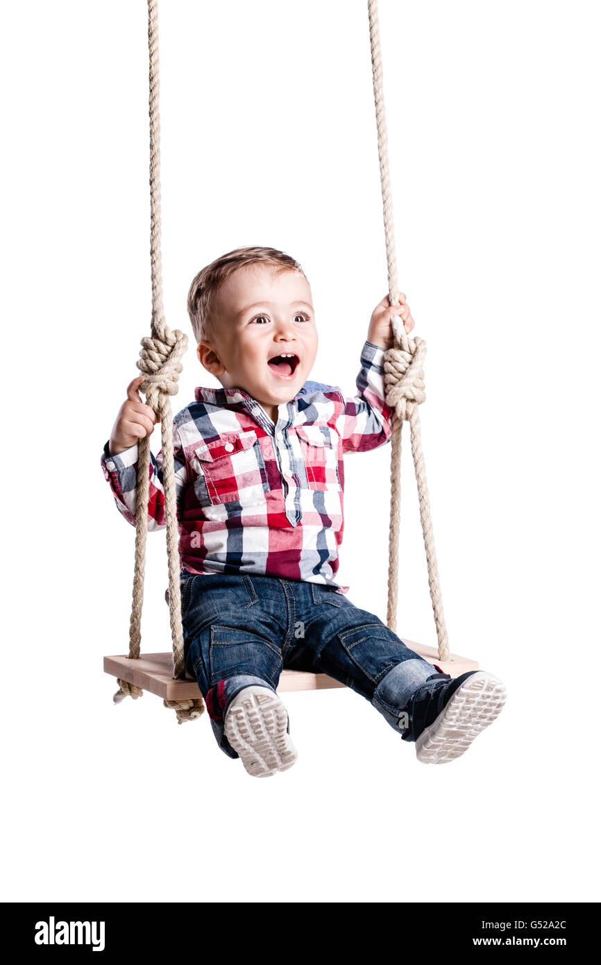 Happy little boy basculante in una oscillazione in legno Foto Stock