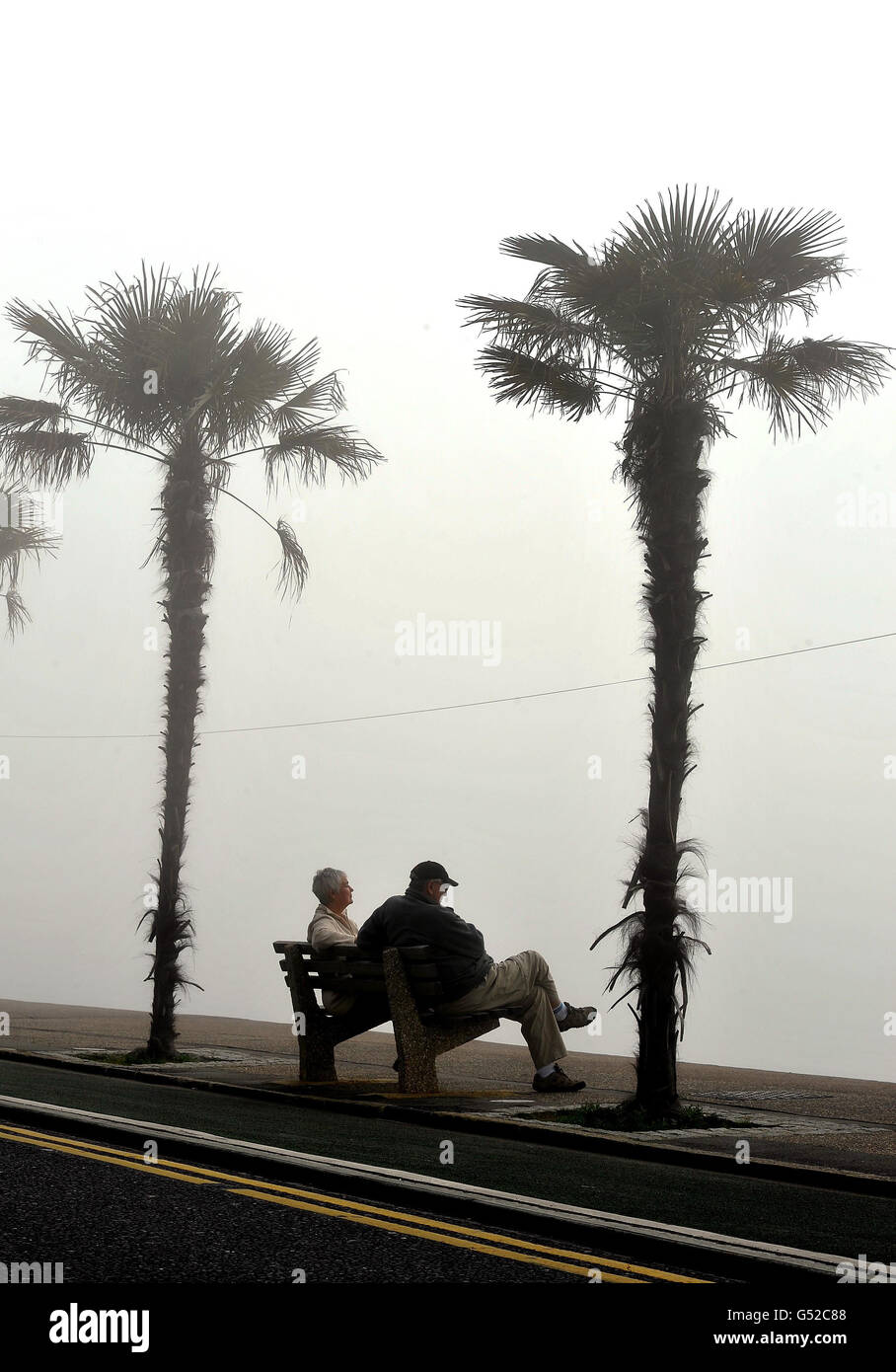 Una coppia si siede su una panca di fronte al mare avvolta dalla nebbia, in attesa della prevista ondata di caldo del fine settimana per raggiungere Southend- on-Sea, Essex. Foto Stock