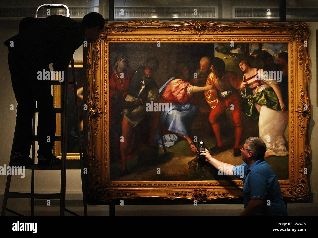 Tecnico logistico David Coia (a sinistra) e tecnico di illuminazione Fraser Campbell (a destra) disporre le luci accanto al Cristo dipinto e l'Adolteressa di Tiziano, in vista dell'apertura della mostra essenza della bellezza: 500 anni di arte italiana, alla Kelvingrove Art Gallery and Museum di Glasgow. Foto Stock