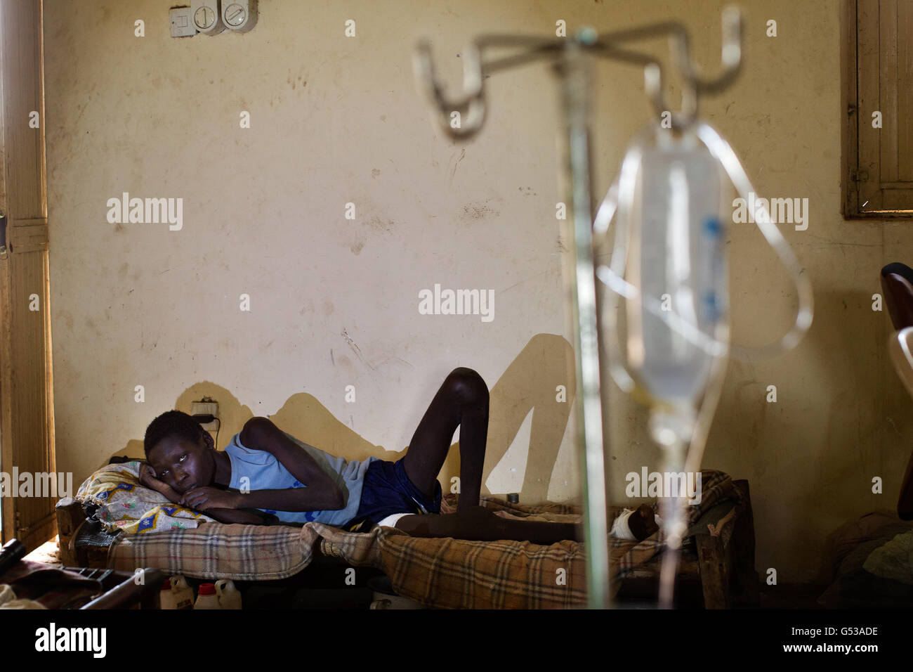 Un ragazzo di 14 anni, ferito nelle sue due gambe dal bombardamento del suo villaggio nella clinica di Bunj, che si prende cura di persone dal campo profughi di Doro a Bunj, Maban, nell'Alto Nilo Blu Stato del nord-est Sudan del Sud, Africa. La regione ha recentemente sofferto di gravi scontri tra il Nord e il Sud Sudan, con la conseguenza di decine di migliaia di persone costrette a rifugiarsi nei campi profughi come Doro e Jamman e centinaia di morti per i bombardamenti di villaggi e scontri tra gruppi armati rivali. Negli enormi campi profughi, la malattia e la malnutrizione uccidono i giovani, deboli e anziani e con le piogge minacciate Foto Stock