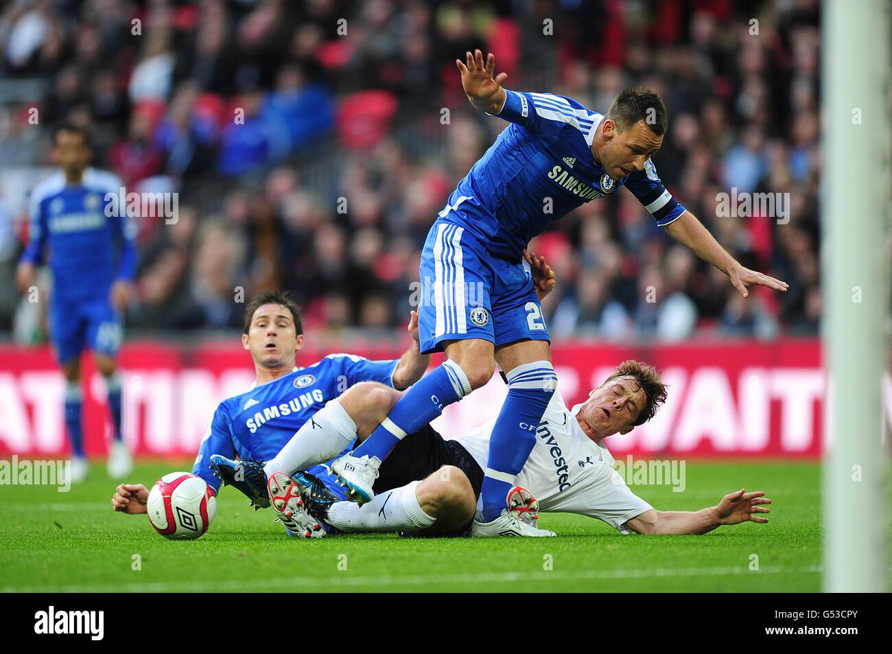 Frank Lampard di Chelsea (a sinistra) e John Terry (in piedi) si uniscono a. Sfida Scott Parker di Tottenham Hotspur Foto Stock