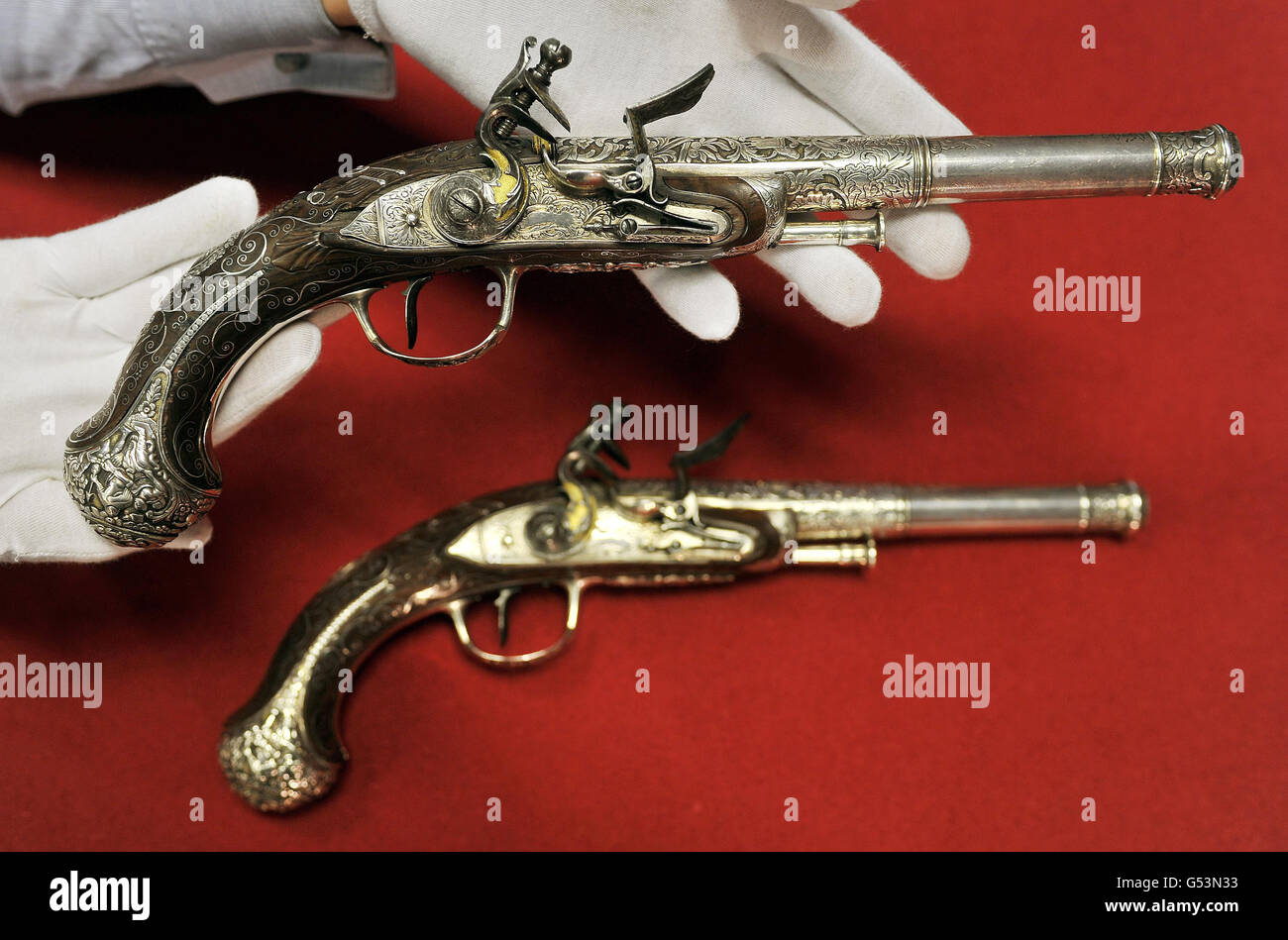 Un lavoratore per le aste di Bonhams tiene un paio di pistole flintlock corrispondenti made in India circa 1785 e valutato a £30,000 a £40,000 come parte dell'asta di armi e armature antiche che si terrà domani presso il ramo di Knightsbridge nel centro di Londra. Foto Stock