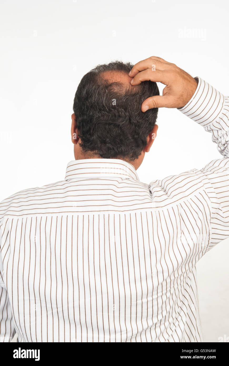 Vista posteriore di un uomo con una macchia calva in piedi contro uno sfondo bianco Foto Stock