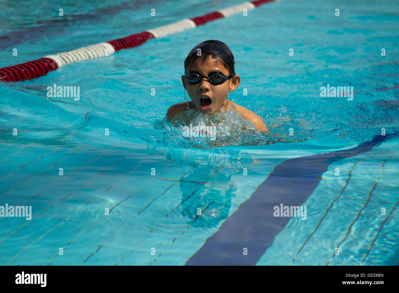 Giovane ragazzo cinese che indossa gli occhiali di protezione e il tappo di nuoto a rana in un pool Foto Stock