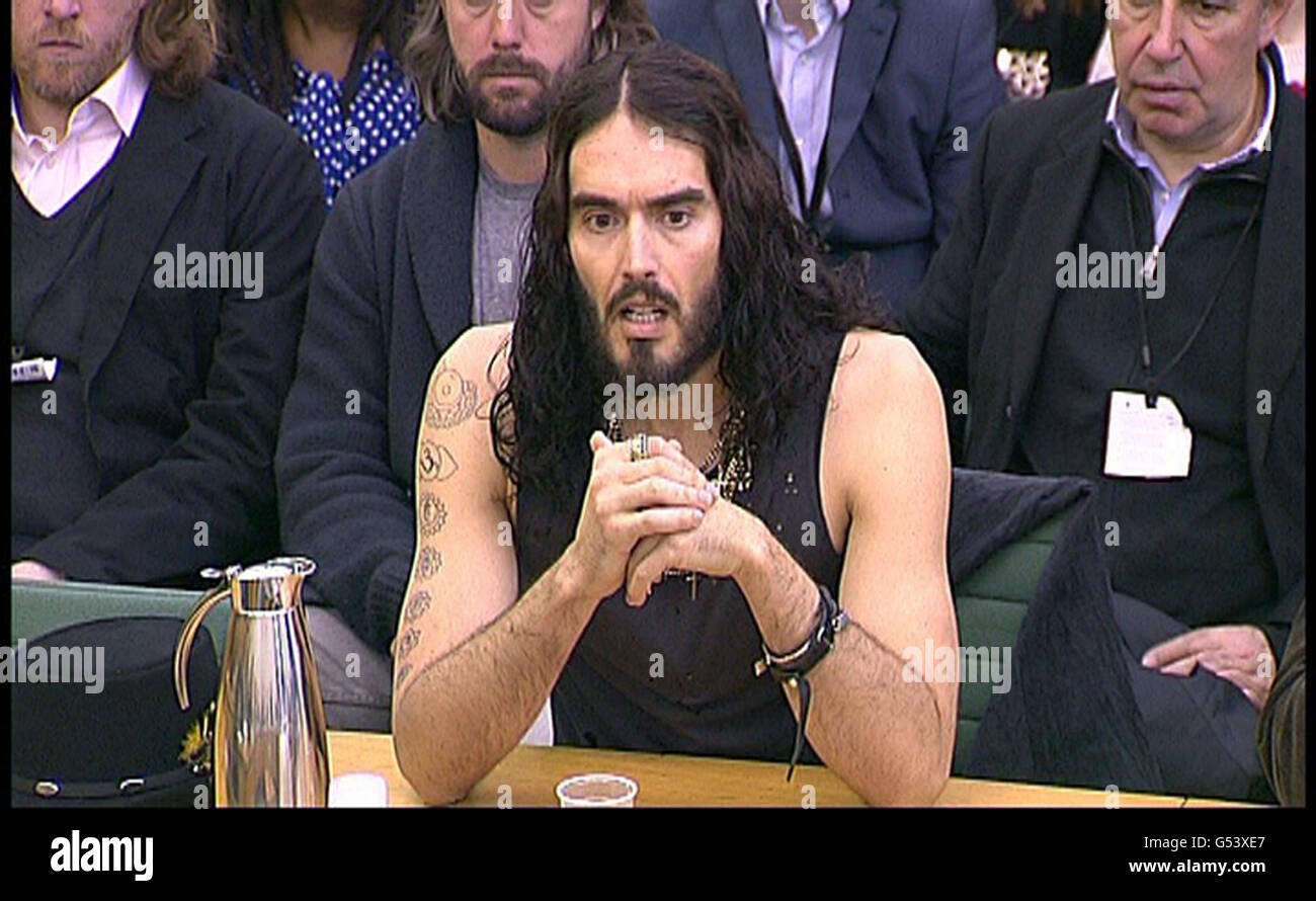 Il comico Russell Brand risponde alle domande sulla politica in materia di droga mentre dà prova alla commissione di selezione degli affari interni alla Camera dei Comuni, Londra. Foto Stock