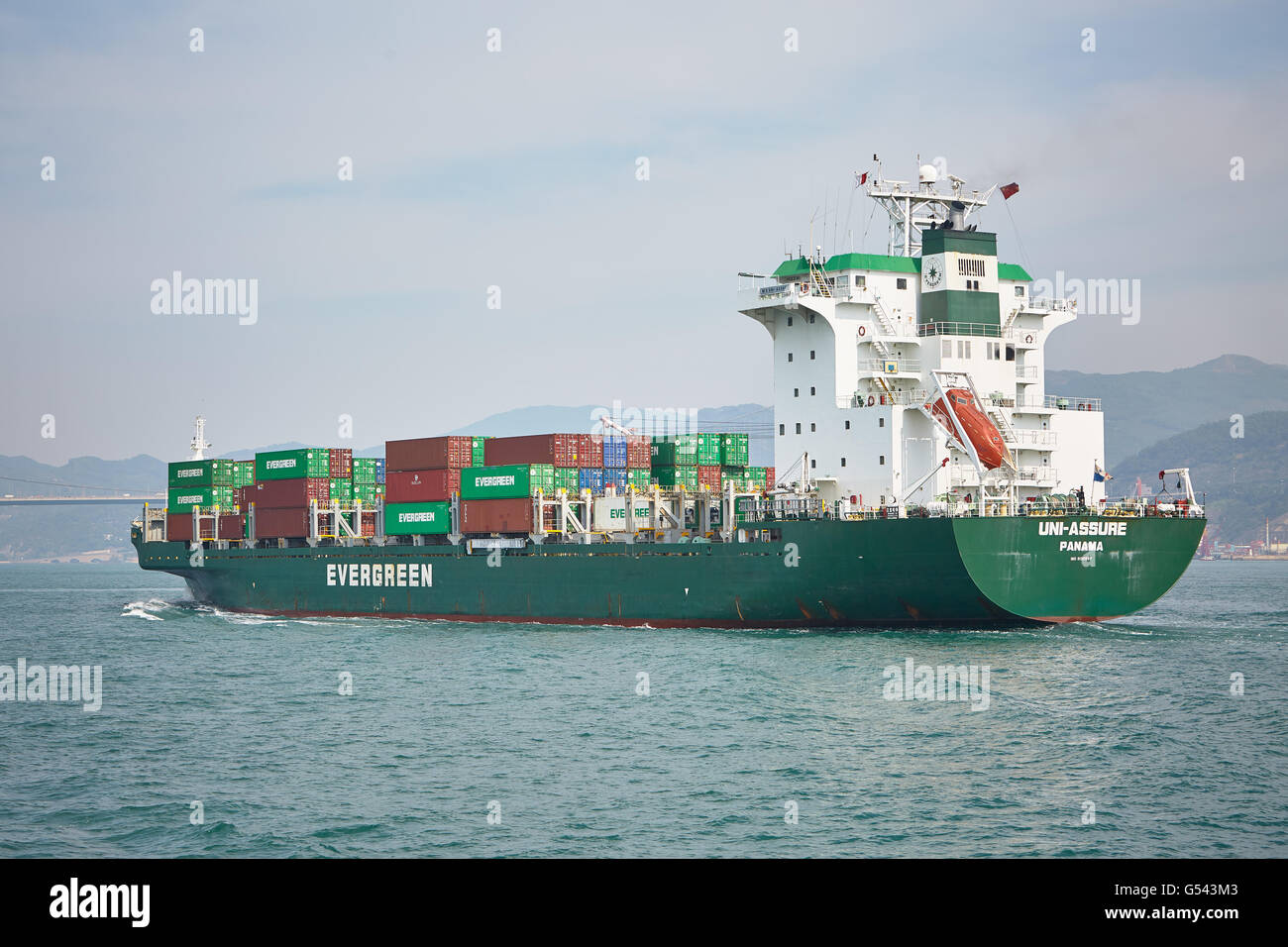 Un container carico nave vela lontano dal terminal per container a Tsing Yi di Hong Kong. Foto Stock