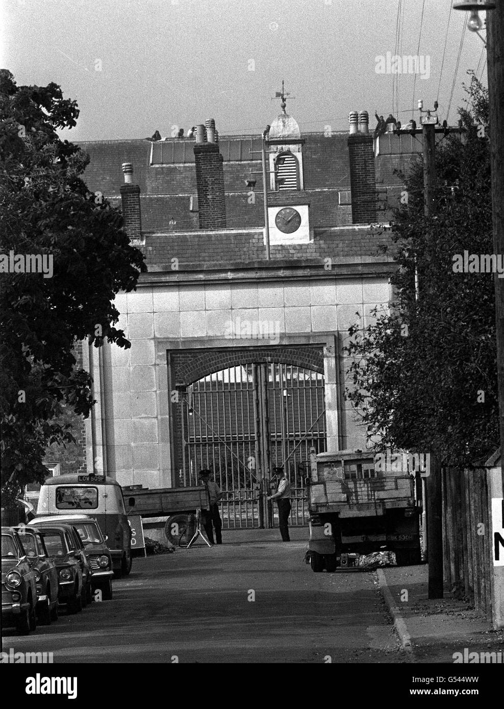 PROTESTA DELLA PRIGIONE DI PARKHURST 1972: I prigionieri della prigione di Parkhurst, Isola di Wight, hanno continuato la loro protesta in solidarietà con i prigionieri della prigione di Albany, che si unisce. Gli uomini possono essere visti lungo il punto del tetto, mentre, sotto, i guarder sono sull'allarme davanti ai cancelli massicci. Foto Stock