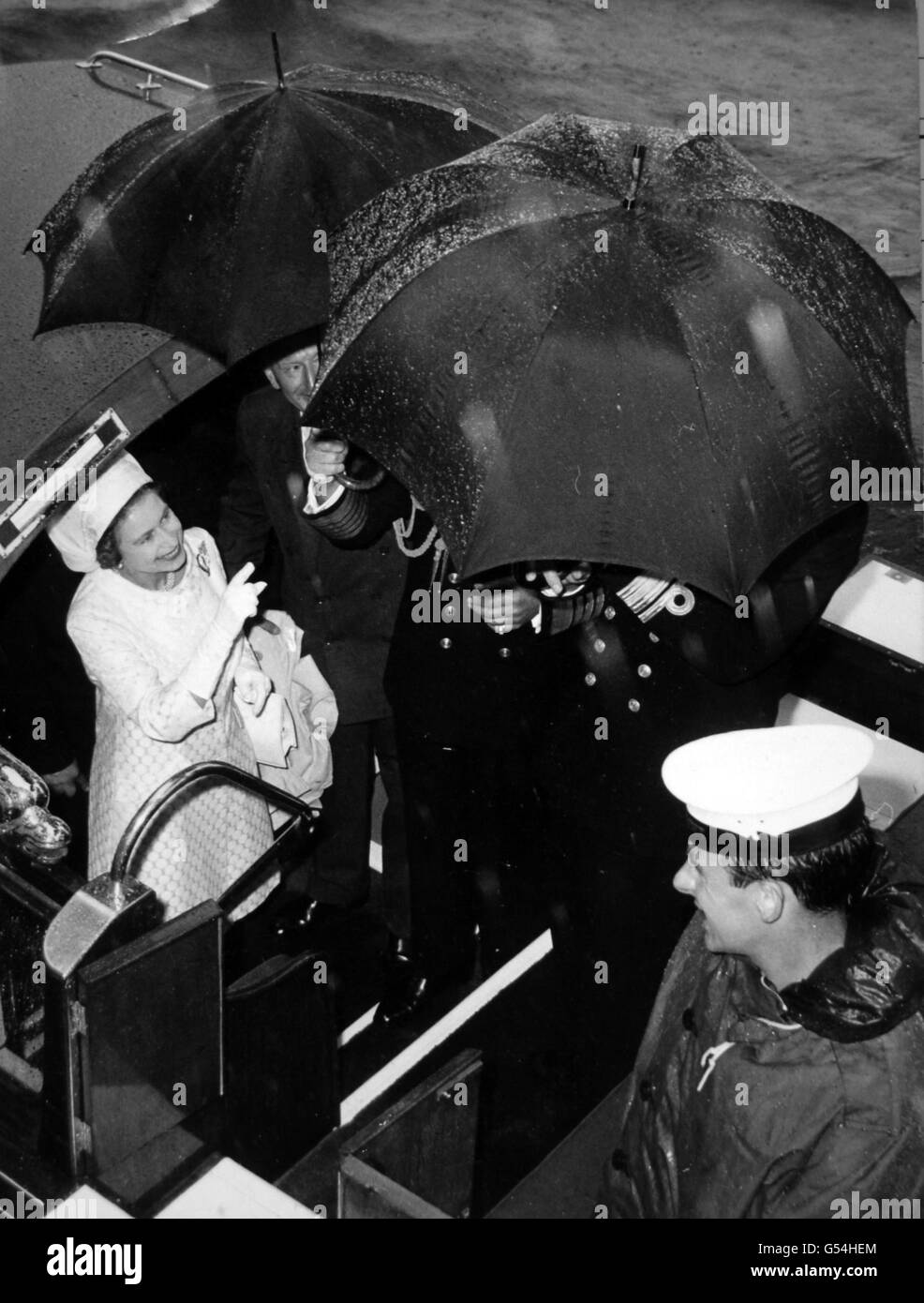 Regina Elisabetta II tra gli ombrelli a bordo di HMS Blake durante la sua visita alle navi della flotta occidentale a Torbay. Foto Stock
